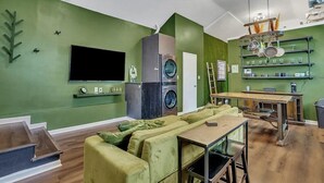 Una sala de estar con paredes verdes, un sofá, televisor y un comedor con mesa y sillas.