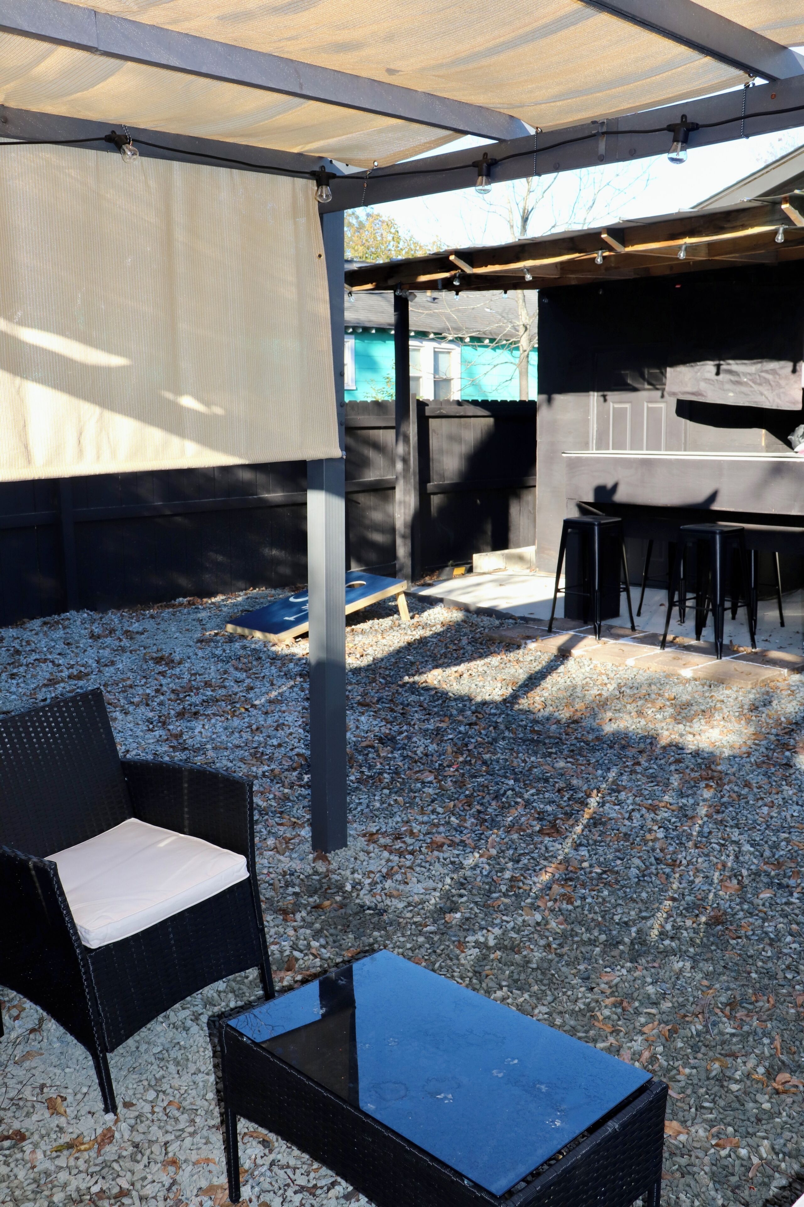 Un patio exterior con zona de estar techada, una mesa y equipo para barbacoa.
