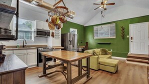 Una cocina con armarios blancos, una mesa de madera y una pared verde.