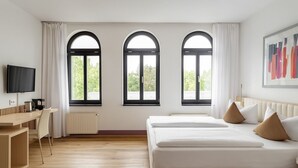A hotel room with a bed, a desk, a chair, and a TV. - Hotel Villa Noel – Central Station Dresden (Dresden)