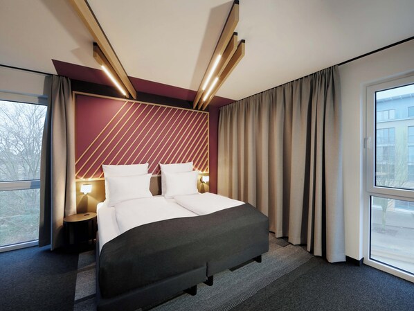 A hotel room with a bed, bedside tables, a window, and curtains. - B&B HOTEL Frankfurt-Oder (Frankfurt an der Oder)