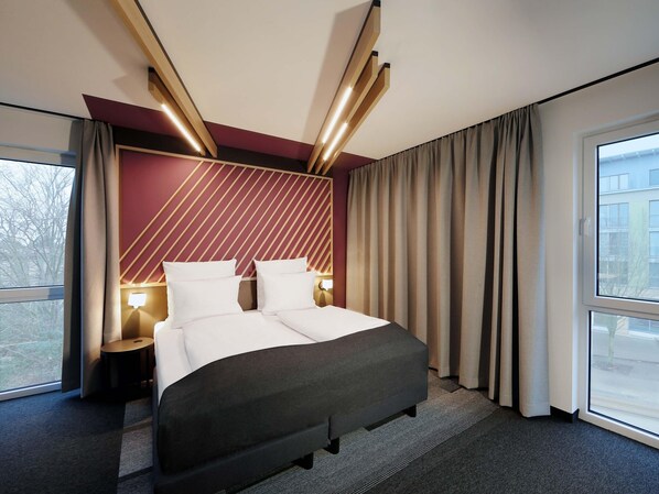 Une chambre d’hôtel avec un lit, des tables de chevet, une fenêtre et une vue sur l’extérieur.