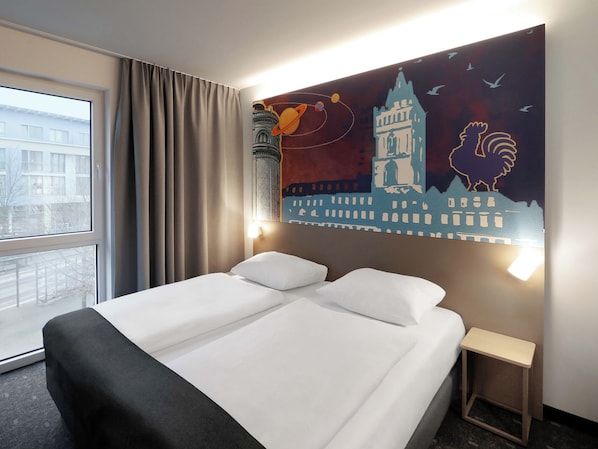 A hotel room with a large bed, a nightstand, a window with curtains, and a wall mural. - B&B HOTEL Frankfurt-Oder (Frankfurt an der Oder)