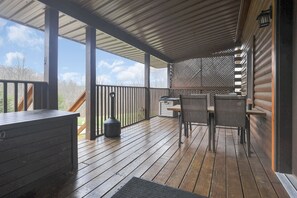 Terrassa exterior coberta amb taula i cadires de fusta, una barbacoa i un banc amb espai d'emmagatzematge.