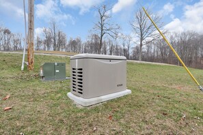 Eine mobile Klimaanlage mit dem Aufdruck "KOHLER" auf einer Wiese, im Hintergrund kahle Bäume.