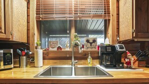 Une cuisine avec des meubles en bois, un évier en acier inoxydable, une machine à café et des décorations de Noël.