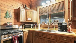 Une cuisine avec des meubles de rangement en bois, une cuisinière, un four à micro-ondes et un évier.