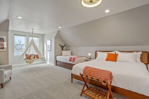 A spacious bedroom with a large bed, a smaller bed, a hanging chair, and a ceiling fan. - Spacious Downtown Location | 4BA, 2 Kitchens + Game Room (Cheyenne)