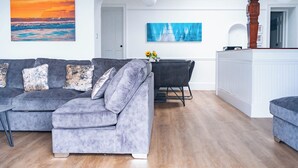 A living room with a grey sofa, a dining table with chairs, and a white cabinet. - Breathtaking 180° Ocean Views (Ventnor)