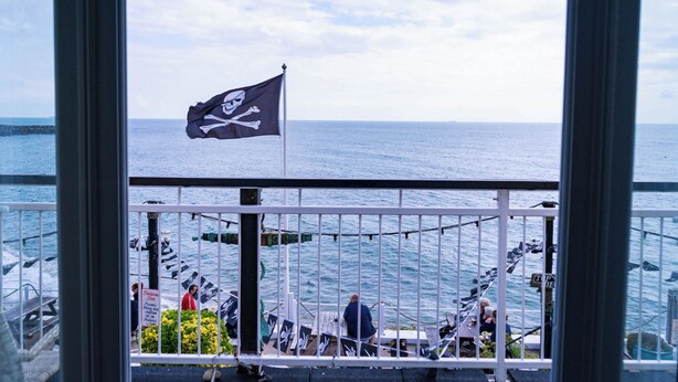 A balcony with a view of the sea, a flag, and some plants. - Breathtaking 180° Ocean Views (Ventnor)