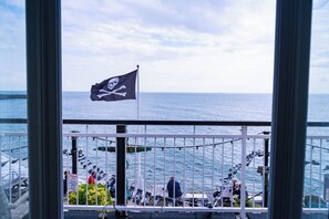 A balcony with a view of the sea, a flag, and some plants. - Breathtaking 180° Ocean Views (Ventnor)