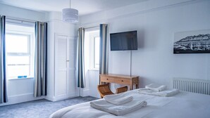 A hotel room with a bed, a desk, a chair, a TV, and a window with curtains. - Breathtaking 180° Ocean Views (Ventnor)