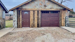 Un garaje rústico con fachada de piedra, puerta de madera y un gran portón.