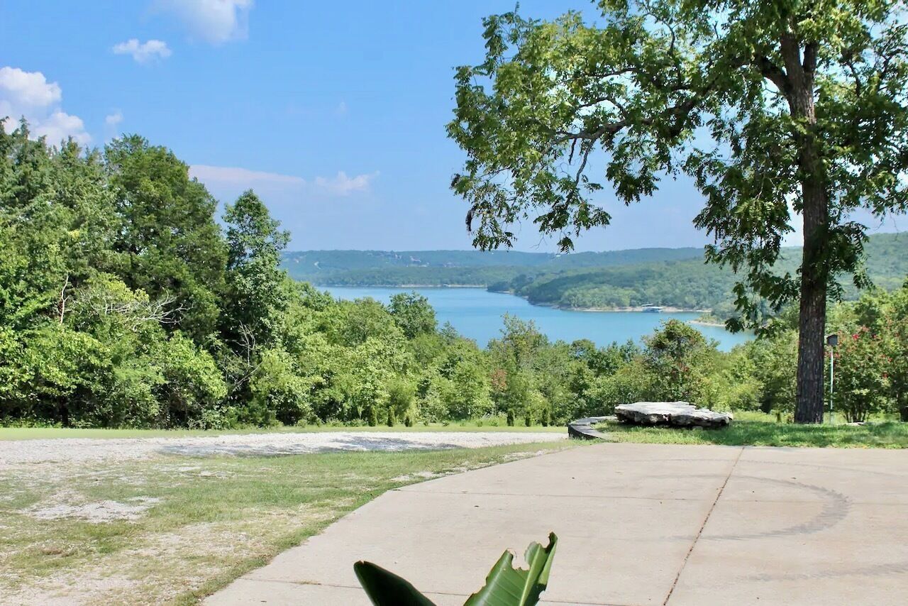 A paved area with a view of a lake and surrounding trees.