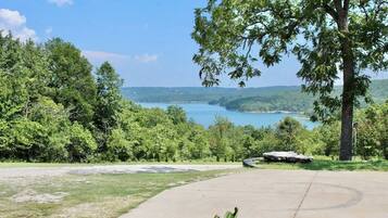 A paved area with a view of a lake and surrounding trees.