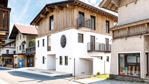 Un edificio moderno con facciata in legno e sezione inferiore bianca, con un logo circolare e un balcone.
