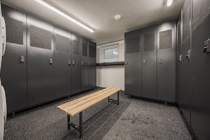 A locker room with grey lockers, a wooden bench, and a window. - Apartment in Kirchberg Near Ski Lift (Kirchberg in Tirol)