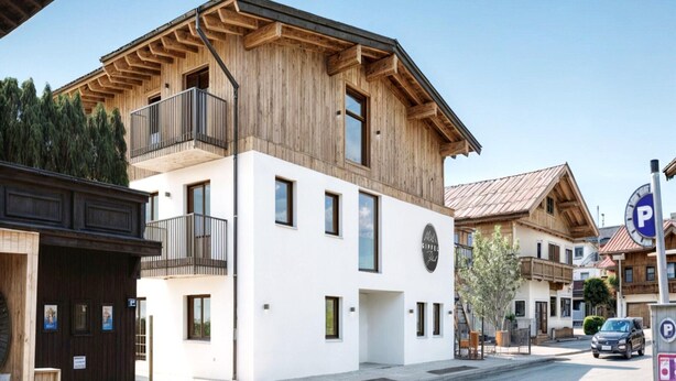 Un edificio moderno con facciata in legno, un balcone e un'insegna che indica un ristorante.