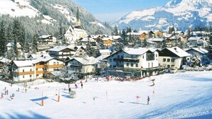 Un villaggio innevato con case in legno tradizionali, una chiesa e una pista da sci.
