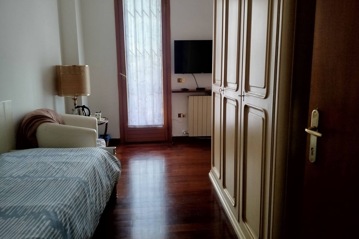 Ein Hotelzimmer mit Bett, Schreibtisch, Fernseher und Kleiderschrank.