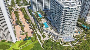 A high-rise hotel with multiple balconies, a swimming pool, and landscaped areas.