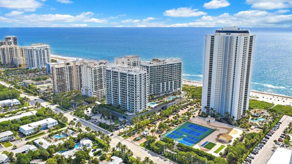 A high-rise hotel with multiple floors, a pool area, and a view of the ocean.