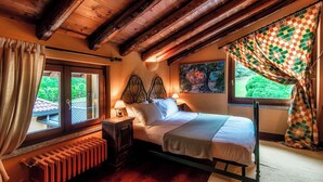 A bedroom with a wooden ceiling, a bed with a headboard, a radiator, and curtains. - Villa Oasi (Canzo)