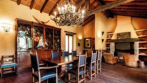 A dining area with a wooden table and chairs, a chandelier, and a fireplace. - Villa Oasi (Canzo)