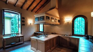 A spacious kitchen with a large island, wooden cabinetry, and a built-in stove. - Villa Oasi (Canzo)