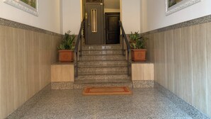 Eine Treppe mit Handlauf, Blumentöpfen und Fußmatte am unteren Ende.