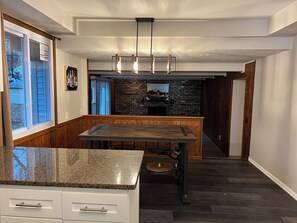 A kitchen with a wooden bench, granite countertop, and a hanging light fixture.