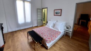 Una camera da letto con un letto, una panca, un comodino, un quadro incorniciato e una porta che dà su un'altra stanza.
