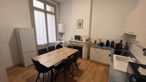 Una cucina funzionale con tavolo, sedie, frigorifero, lavatrice e lavandino.