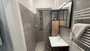 Un bagno stretto con un lavandino bianco, uno specchio e un porta asciugamani.