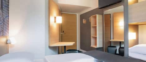 Une chambre d’hôtel équipée d’un lit, d’un bureau, d’une chaise, d’une télévision et d’un miroir.
