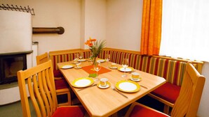Comedor con mesa de madera dispuesta para cuatro, asientos tipo cabina a rayas y un pequeño centro de mesa con planta.