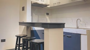 A modern kitchen with white cabinets, a black countertop, and three black stools. - 01 Easy Access Stay, Minutes from Airport on Main Road (Lapu-Lapu City)