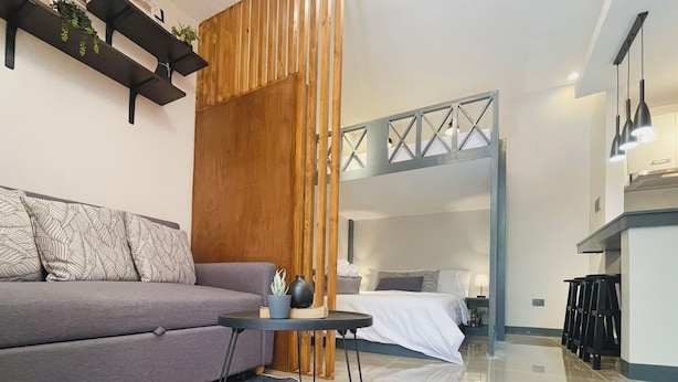 A modern living room with a sofa, a coffee table, and a wooden partition. - 01 Easy Access Stay, Minutes from Airport on Main Road (Lapu-Lapu City)