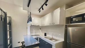A modern kitchen with white cabinets, a stainless steel refrigerator, and a black countertop. - 01 Easy Access Stay, Minutes from Airport on Main Road (Lapu-Lapu City)