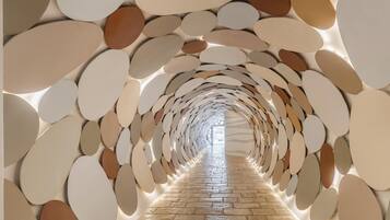 A corridor with a patterned ceiling and a stone floor.