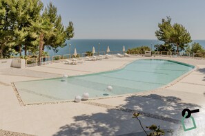 Una piscina al aire libre, sombrillas, sillones reclinables de piscina