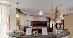 A reception desk with a laptop, a glass fishbowl with pebbles, a vase with pampas grass, and a menu stand. - Hotiday Room Collection - Mattinata Faraglioni (Mattinata)