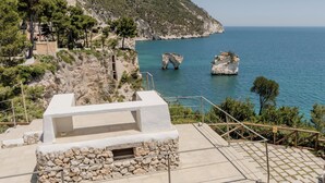 A coastal view with a stone-built structure, a staircase, and a clear blue sea. - Hotiday Room Collection - Mattinata Faraglioni (Mattinata)