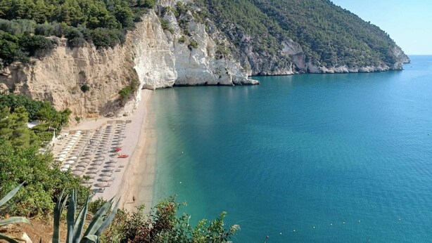 A coastal beach with a rocky cliff and a clear blue sea. - Hotiday Room Collection - Mattinata Faraglioni (Mattinata)