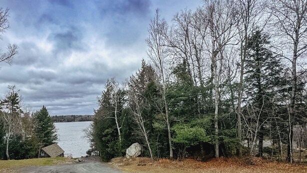 A lakeside view with a wooden deck and a red railing.