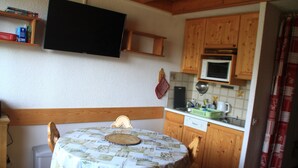 A compact kitchen with wooden cabinets, a microwave, and a table with a patterned tablecloth. - Hameau des 4 Saisons Hsg226 Mountain & View 6 Pers (Chatel)