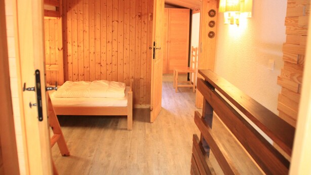 A wooden room with a bed, a bench, and a wall-mounted light fixture. - Hameau des 4 Saisons Hsg226 Mountain & View 6 Pers (Chatel)