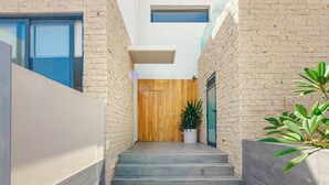 A modern building with a wooden door, a staircase, and a potted plant. - 4-bedroom modern villa with private pool and spectacular views! (La Caleta)