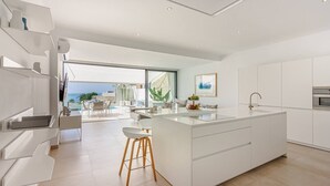 A modern kitchen with a large island, white cabinetry, and a view of the outdoors. - 4-bedroom modern villa with private pool and spectacular views! (La Caleta)