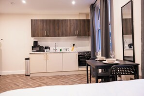 A compact kitchen with wooden cabinets, a microwave, and a coffee maker. - Pillo Rooms Apartments - Chelsea (London)